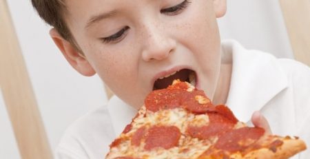 Young child eating large slice of pepperoni pizza