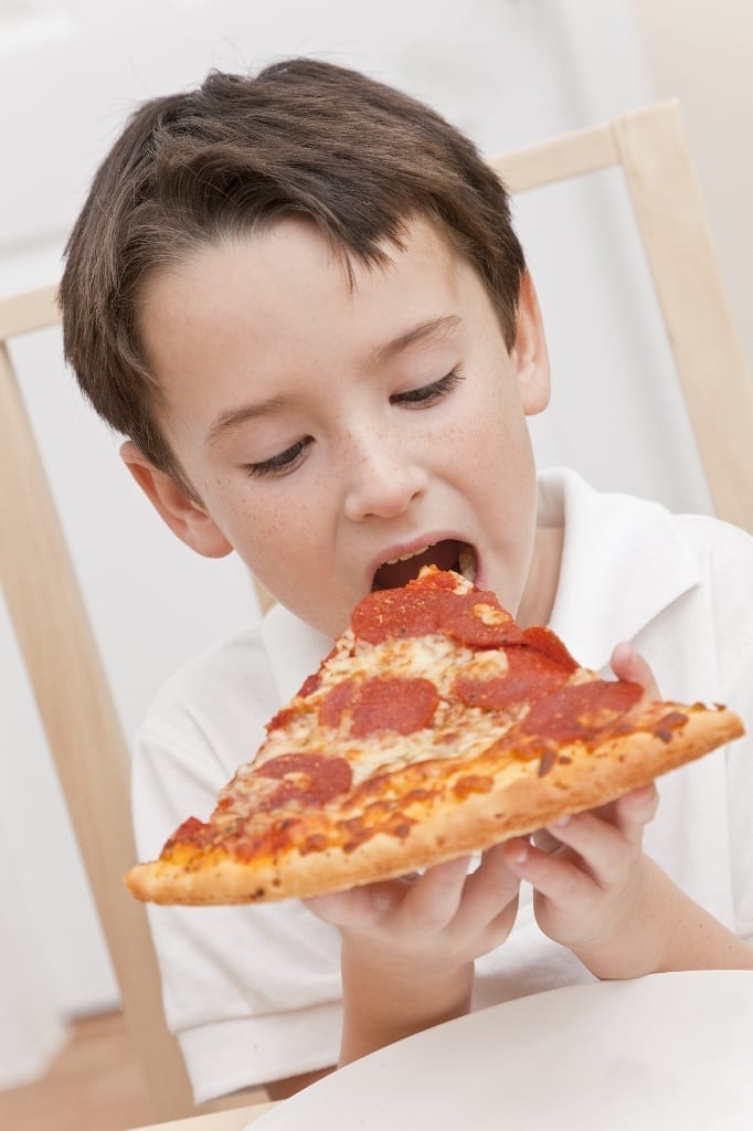Young child eating large slice of pepperoni pizza