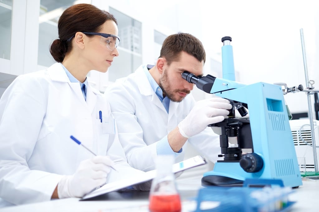 Researchers at a microscope and taking notes