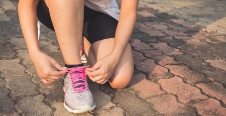 Woman lacing up her pink shoelaces before a short run