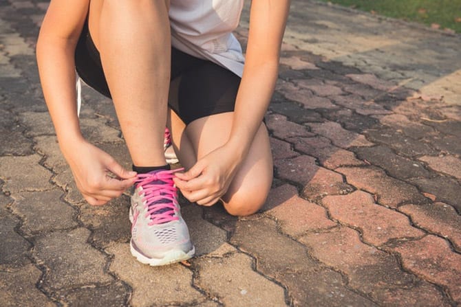 Woman lacing up her pink shoelaces before a short run